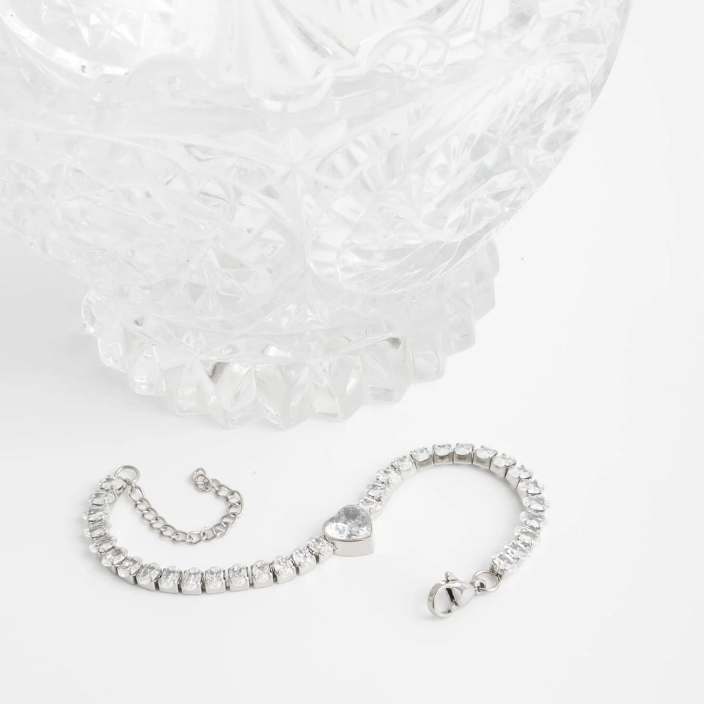 Silver bracelet with heart charm on a white background