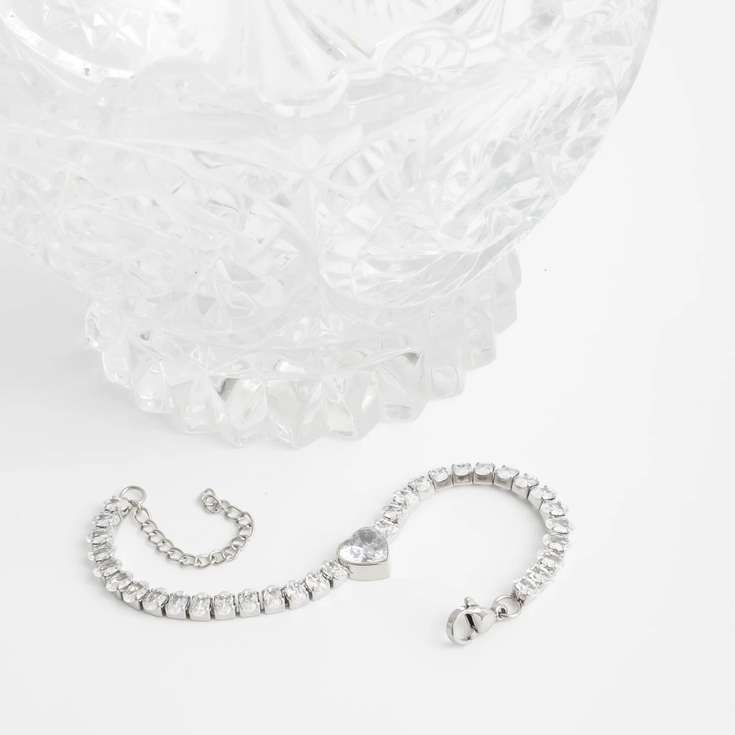 Silver bracelet with heart charm on a white background