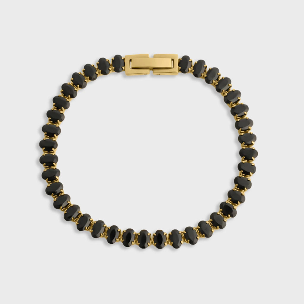 Black beaded bracelet with gold clasp on a light gray background