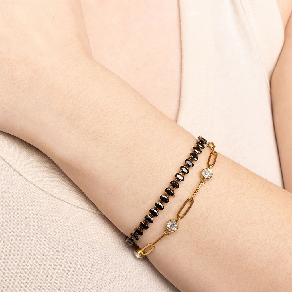 Two bracelets on a person's wrist against a light background