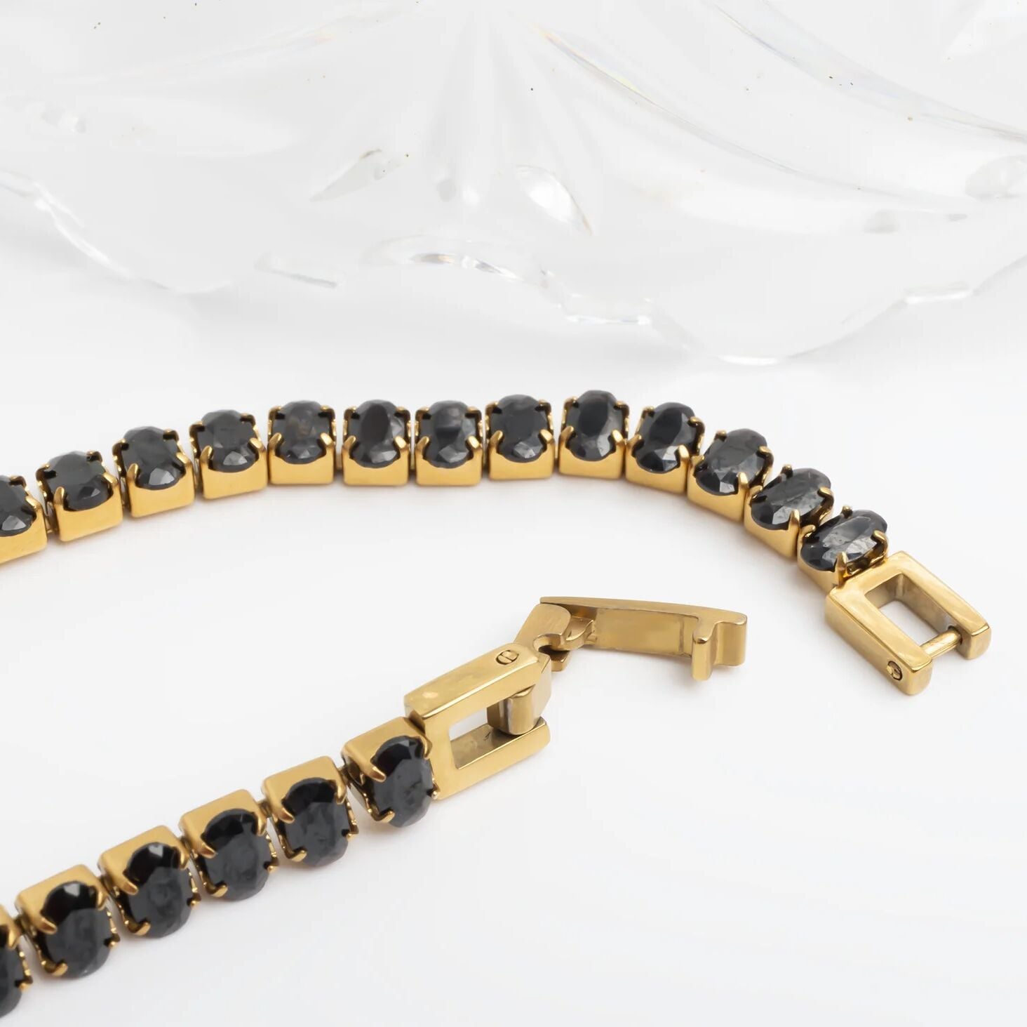 Gold bracelet with black stones on a white background