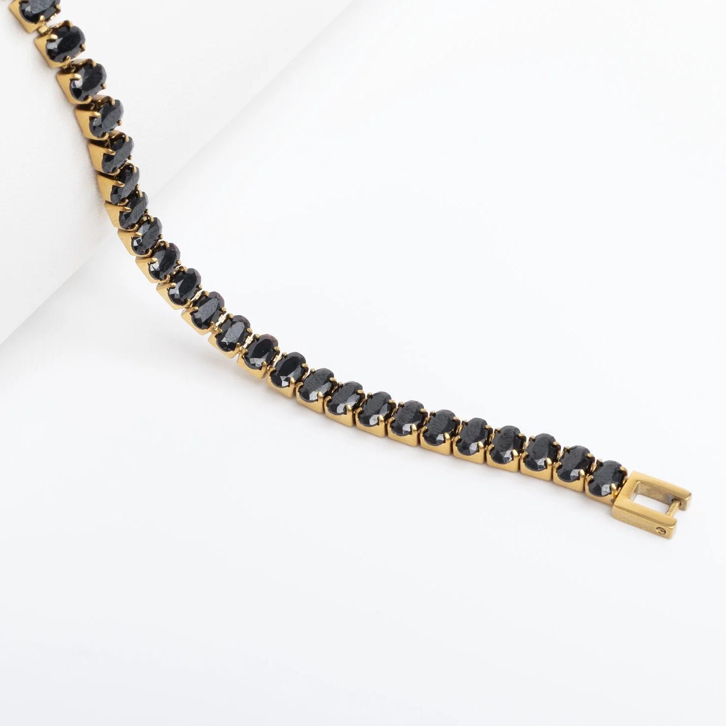 Gold bracelet with black stones on a white background