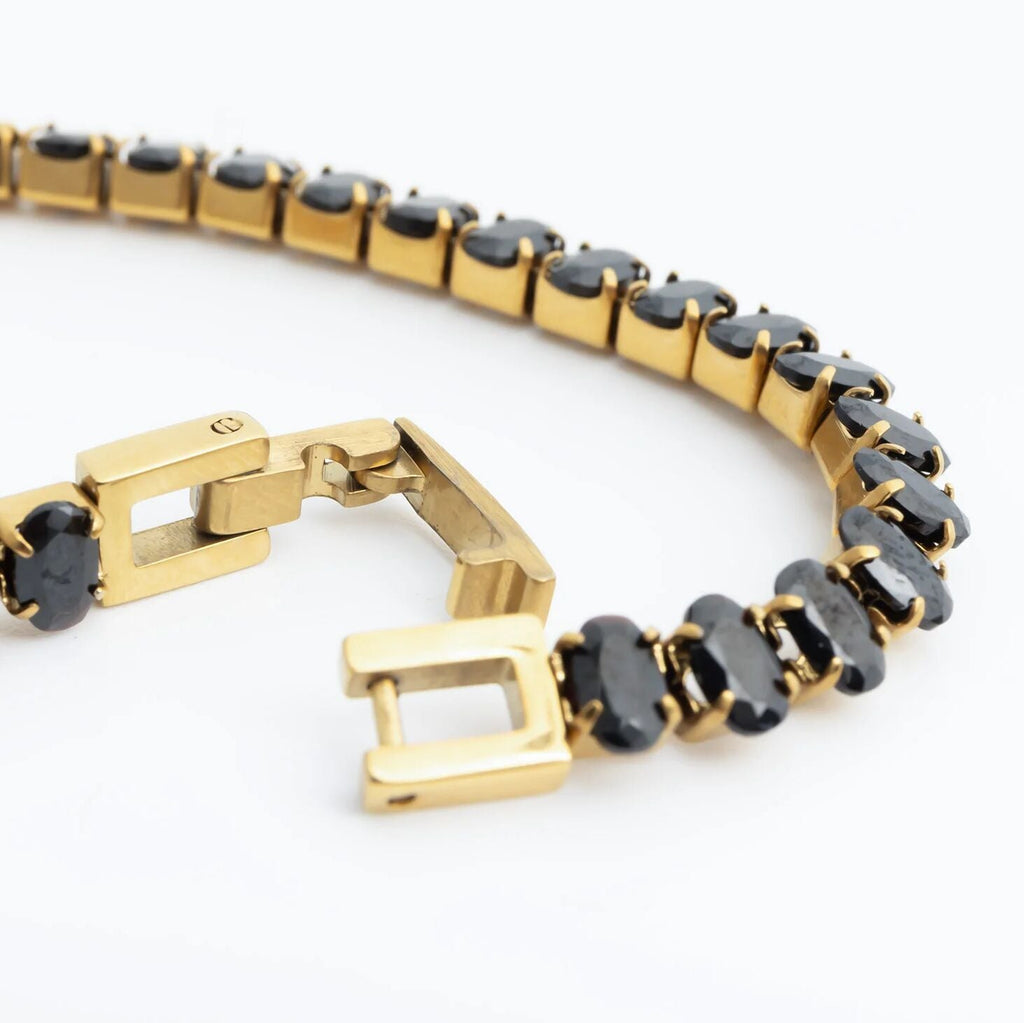 Gold bracelet with black stones on a white background