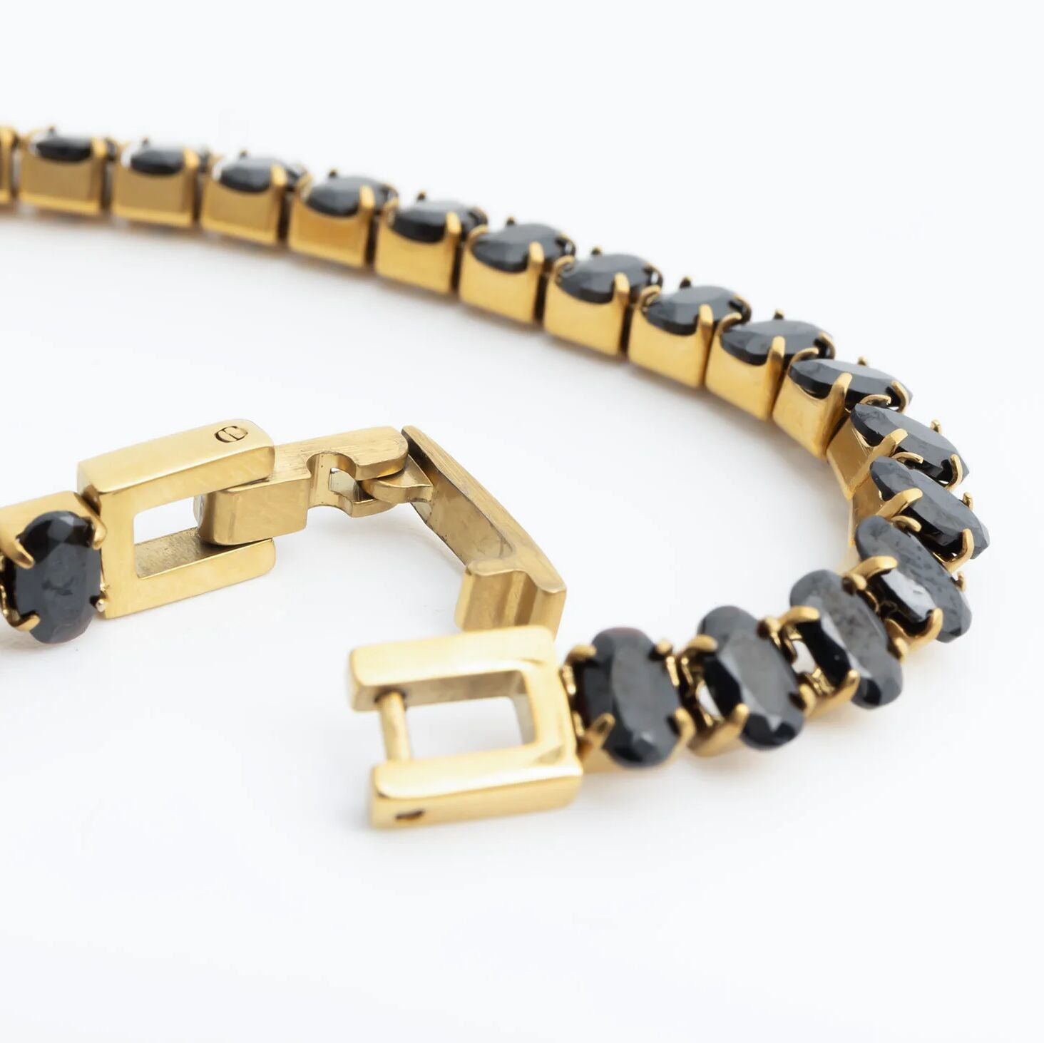 Gold bracelet with black stones on a white background