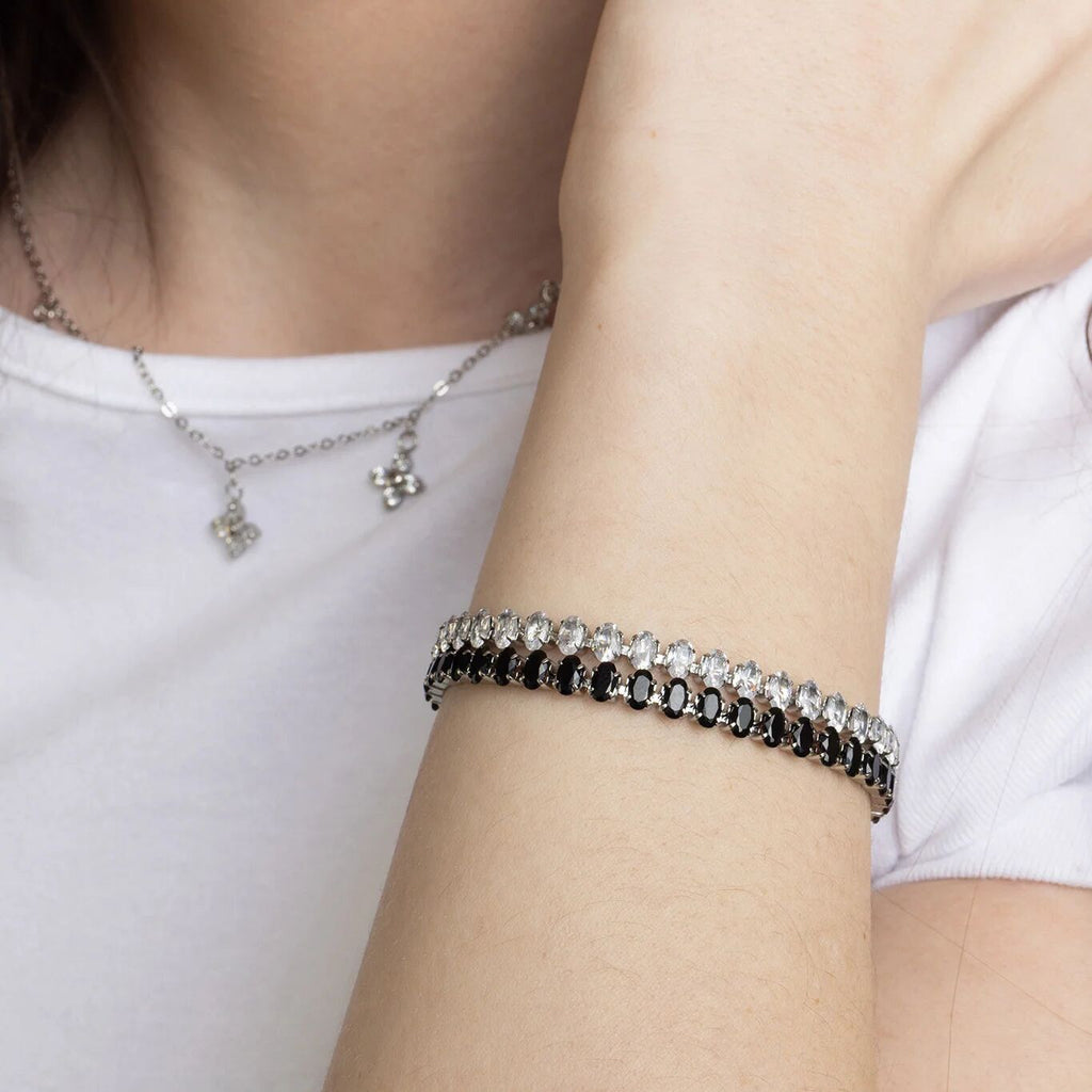 Close-up of a person wearing a bracelet and necklace on a plain background