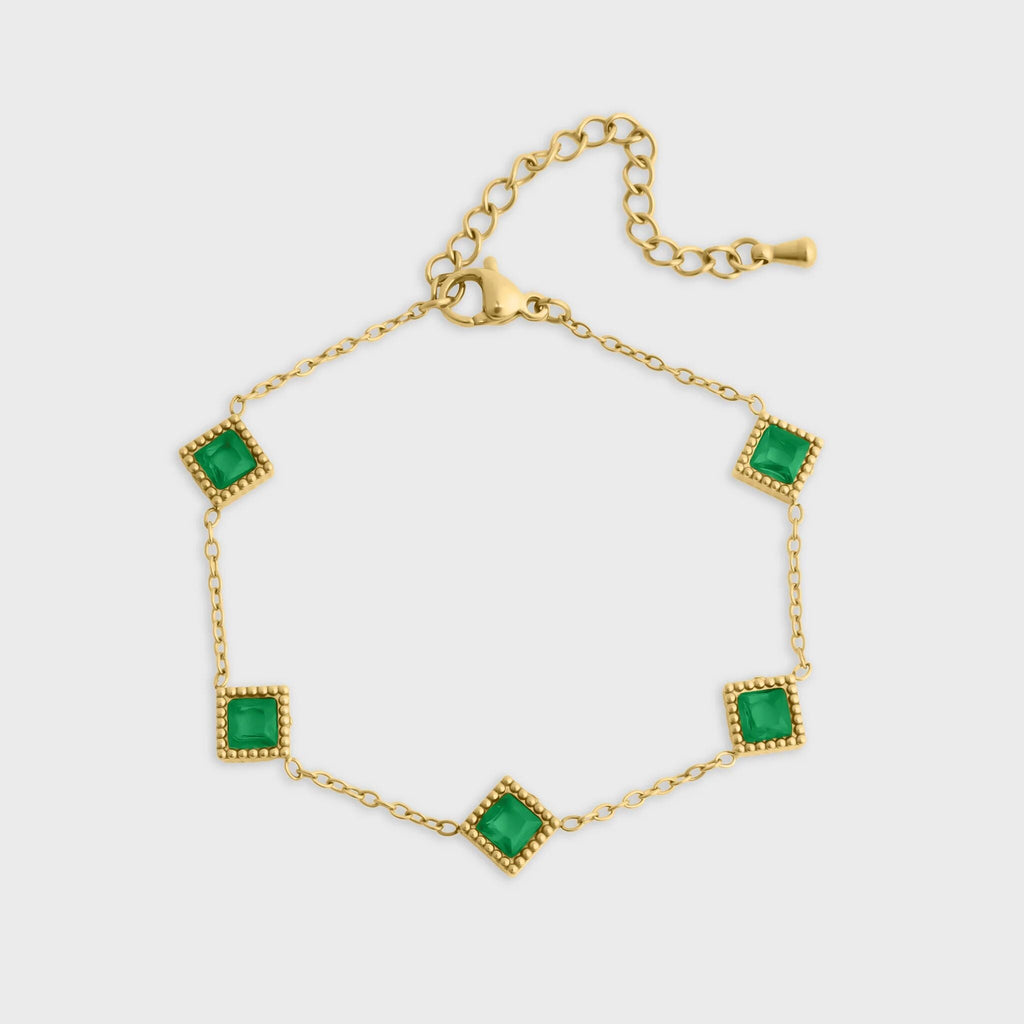 Gold bracelet with green gemstones on a white background