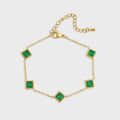 Gold bracelet with green gemstones on a white background