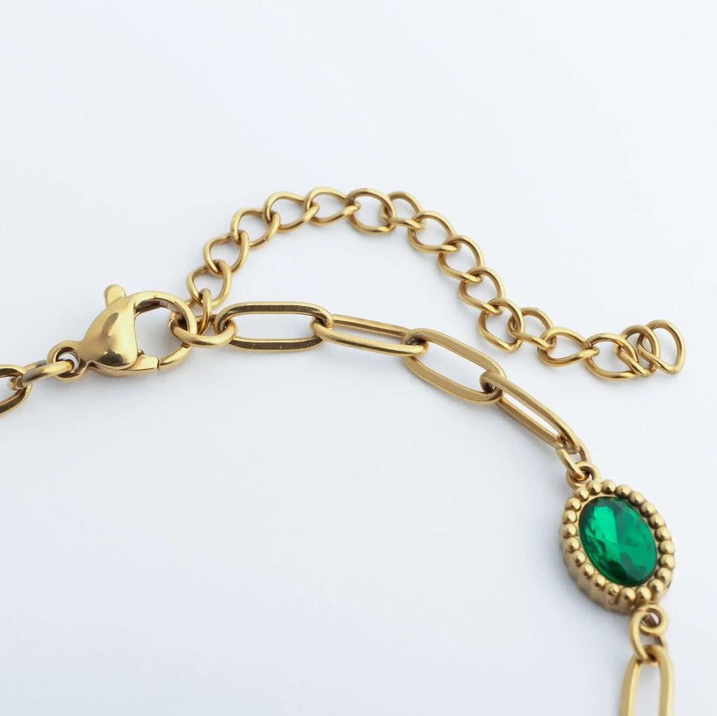 Gold bracelet with a green gemstone on a white background