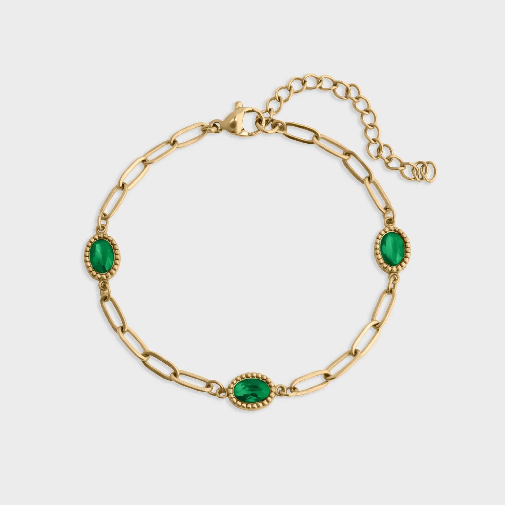 Gold bracelet with green gemstones on a white background