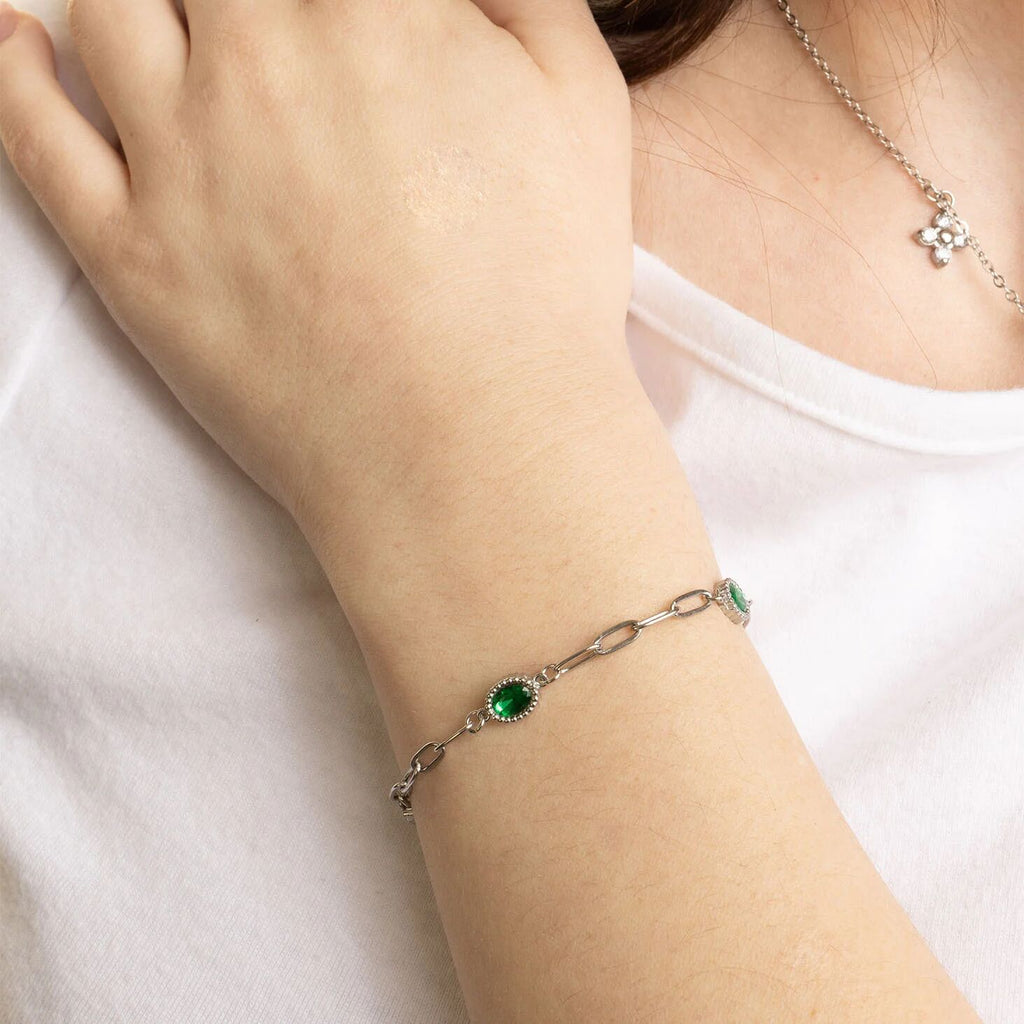 Bracelet with a green gemstone on a wrist against a white background