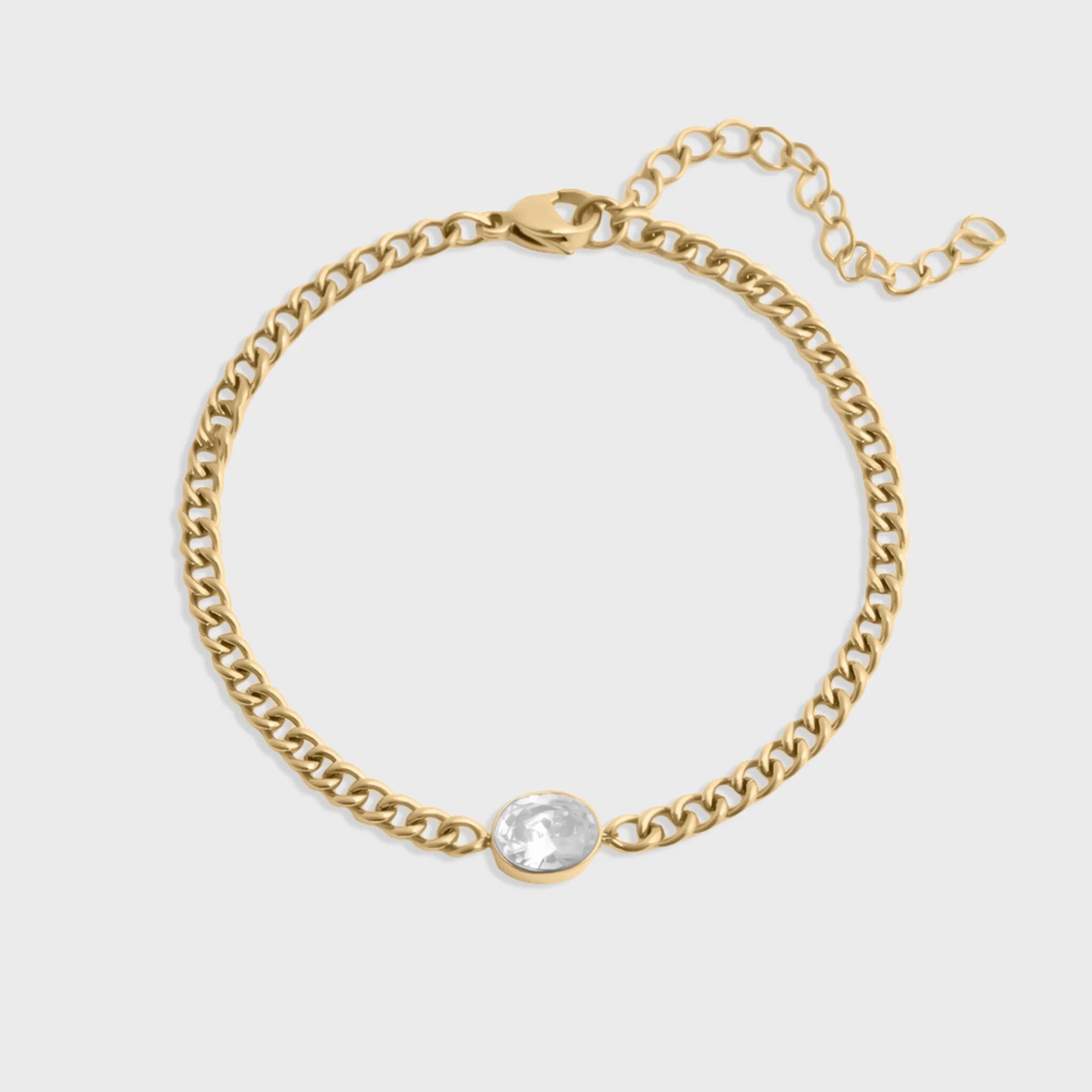 Gold chain bracelet with a clear gemstone on a light gray background