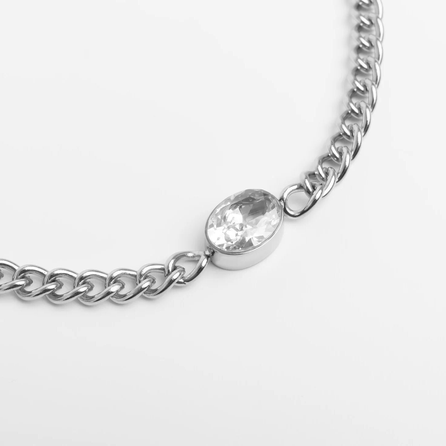 Silver chain bracelet with a clear gemstone on a light gray background