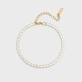 Gold bracelet with clear gemstones on a light gray background