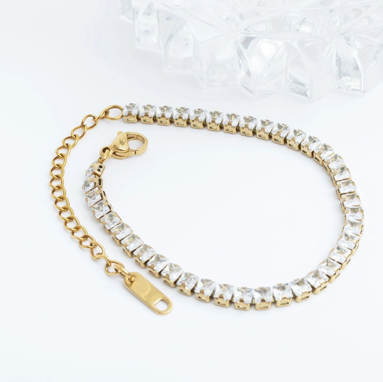Gold bracelet with clear crystals on a white background