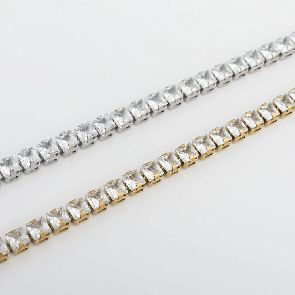 Two strands of clear rhinestone chains, one silver and one gold, on a light gray background.
