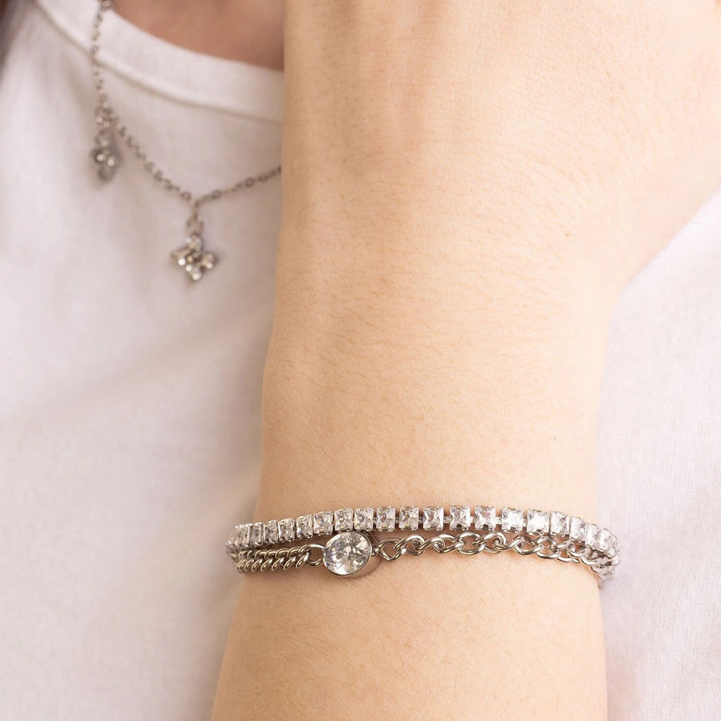 Silver bracelet on a wrist with a neutral background