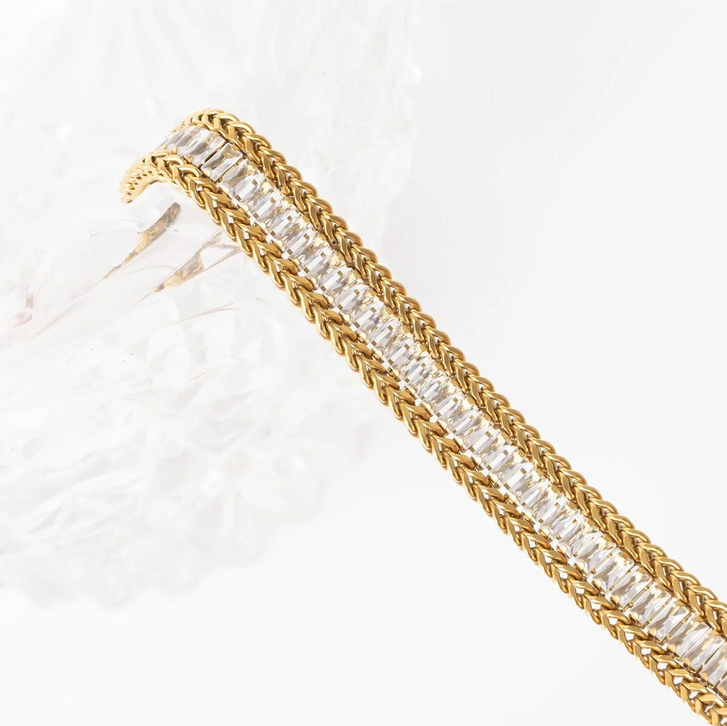 Gold bracelet with clear gemstones on a white background
