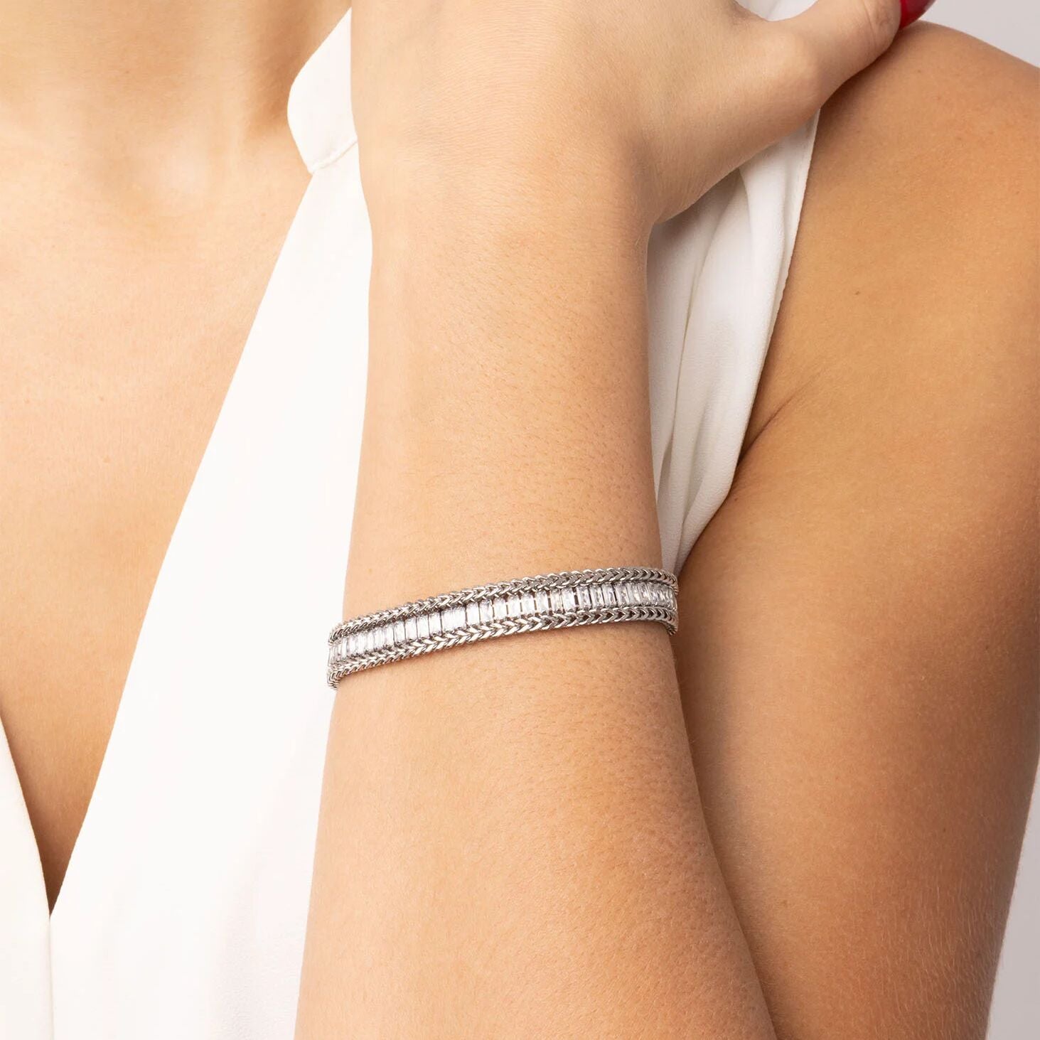 Silver bracelet on a person's wrist with a neutral background