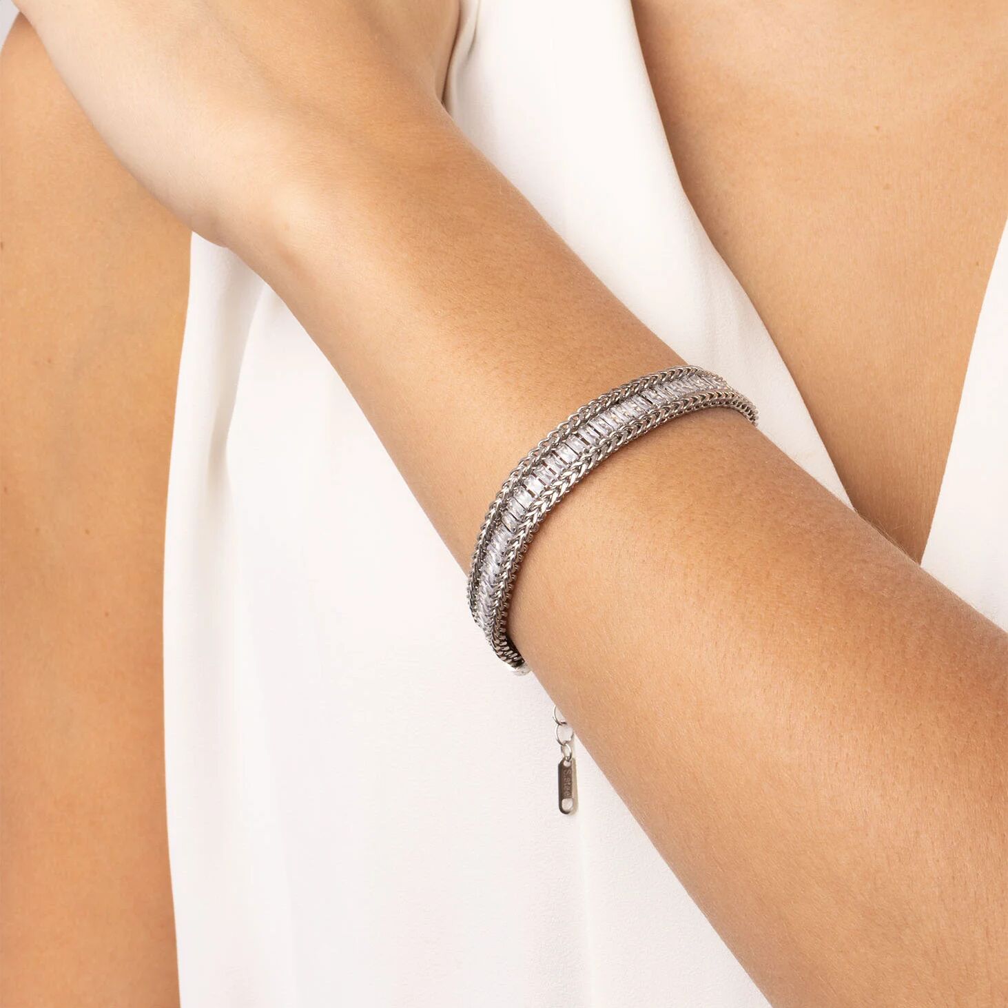 Silver bracelet on a person's wrist against a white background