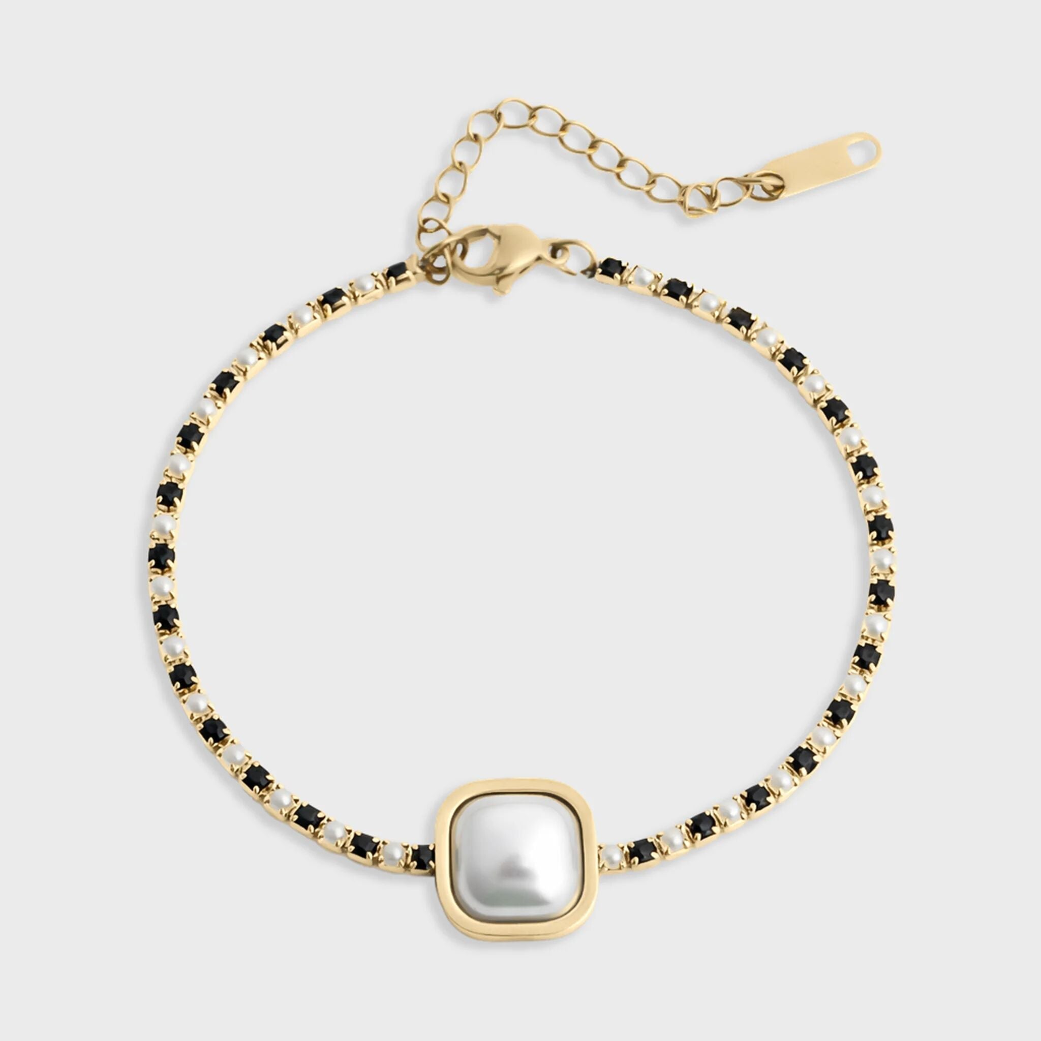 Gold bracelet with a central pearl and black gemstones on a white background