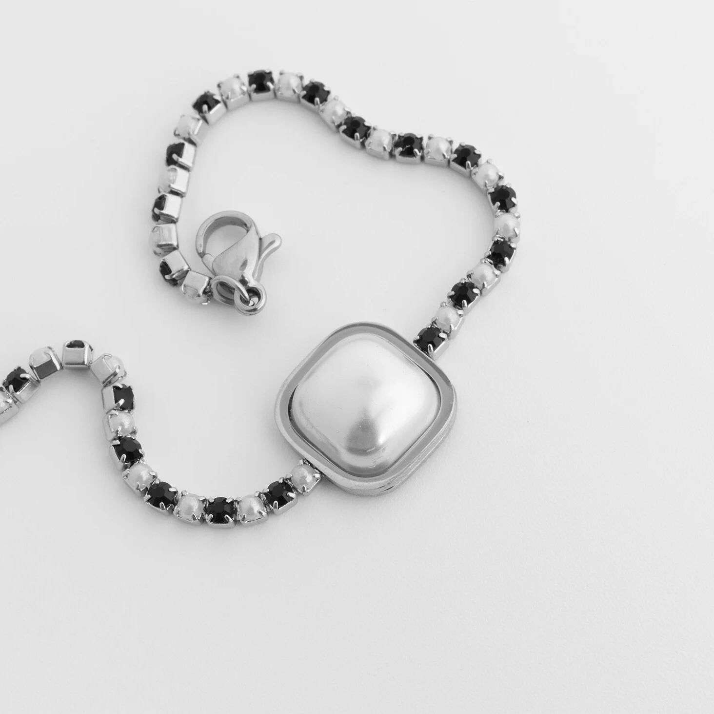 Silver bracelet with black and clear beads on a light gray background