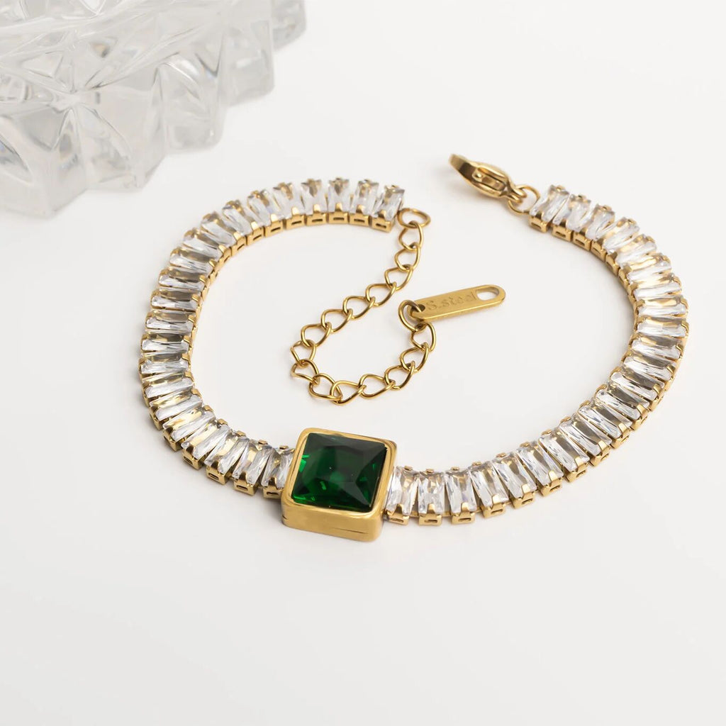 Gold bracelet with green gemstone on a white background
