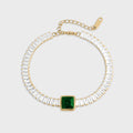 Bracelet with clear gemstones and a green square stone on a white background