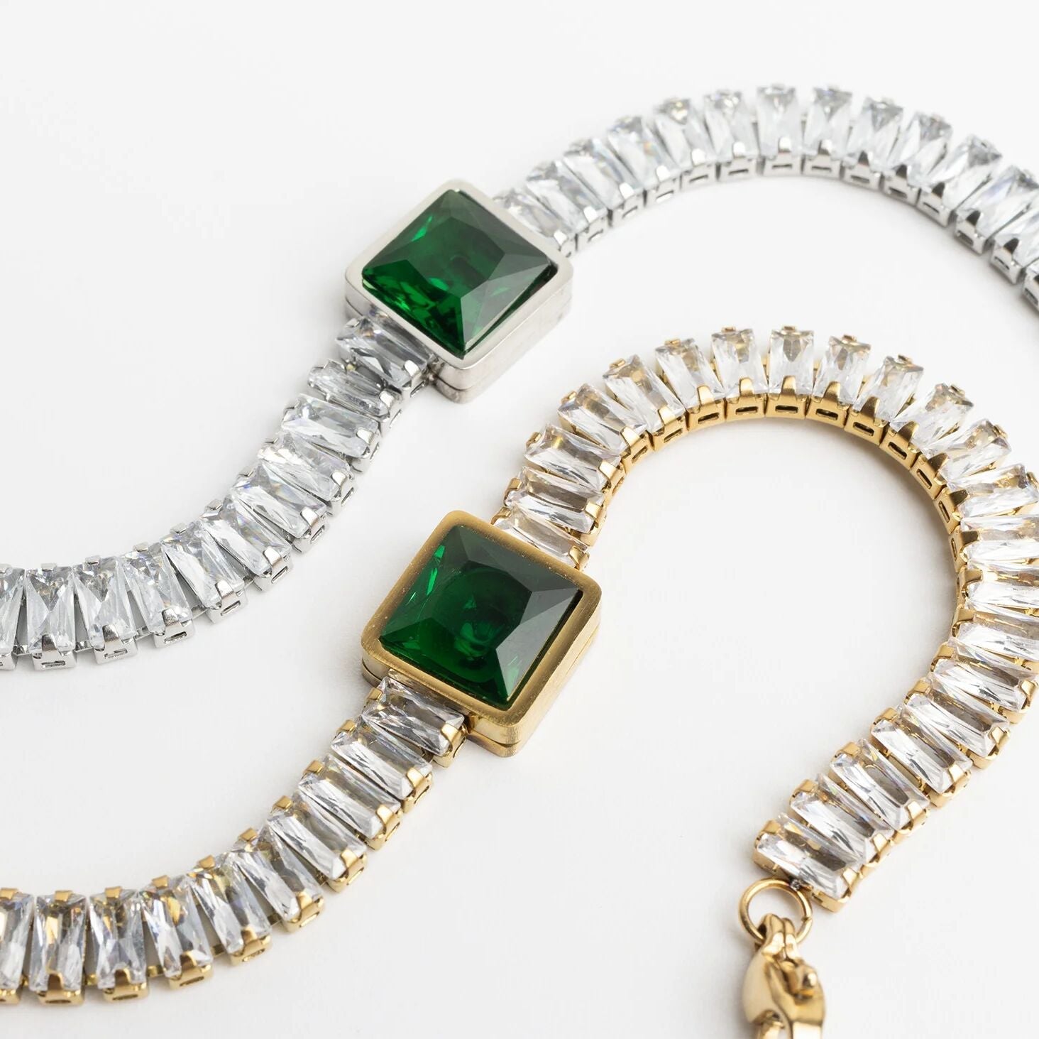 Two bracelets with green gemstones and clear stones on a white background