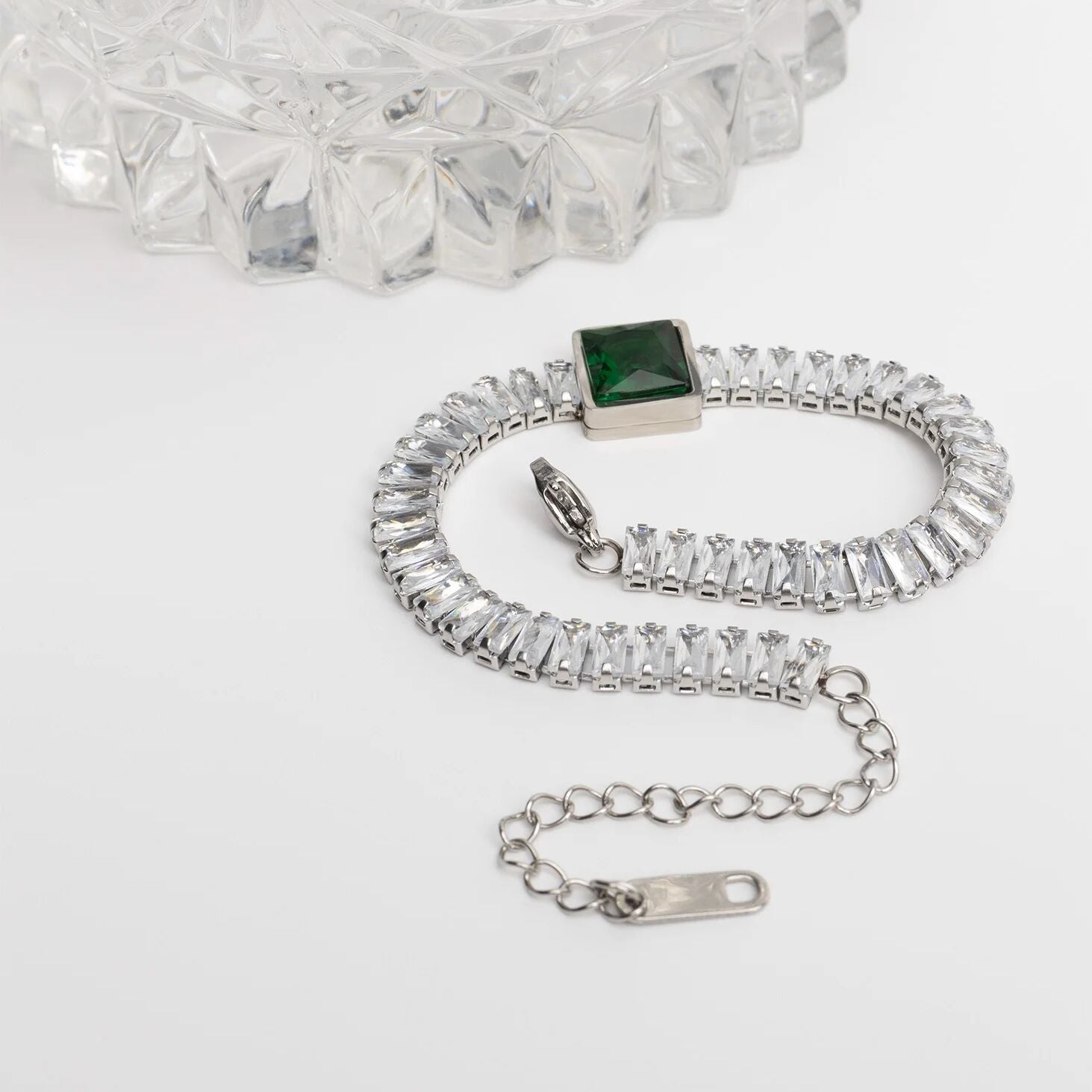 Silver bracelet with a green gemstone on a white background