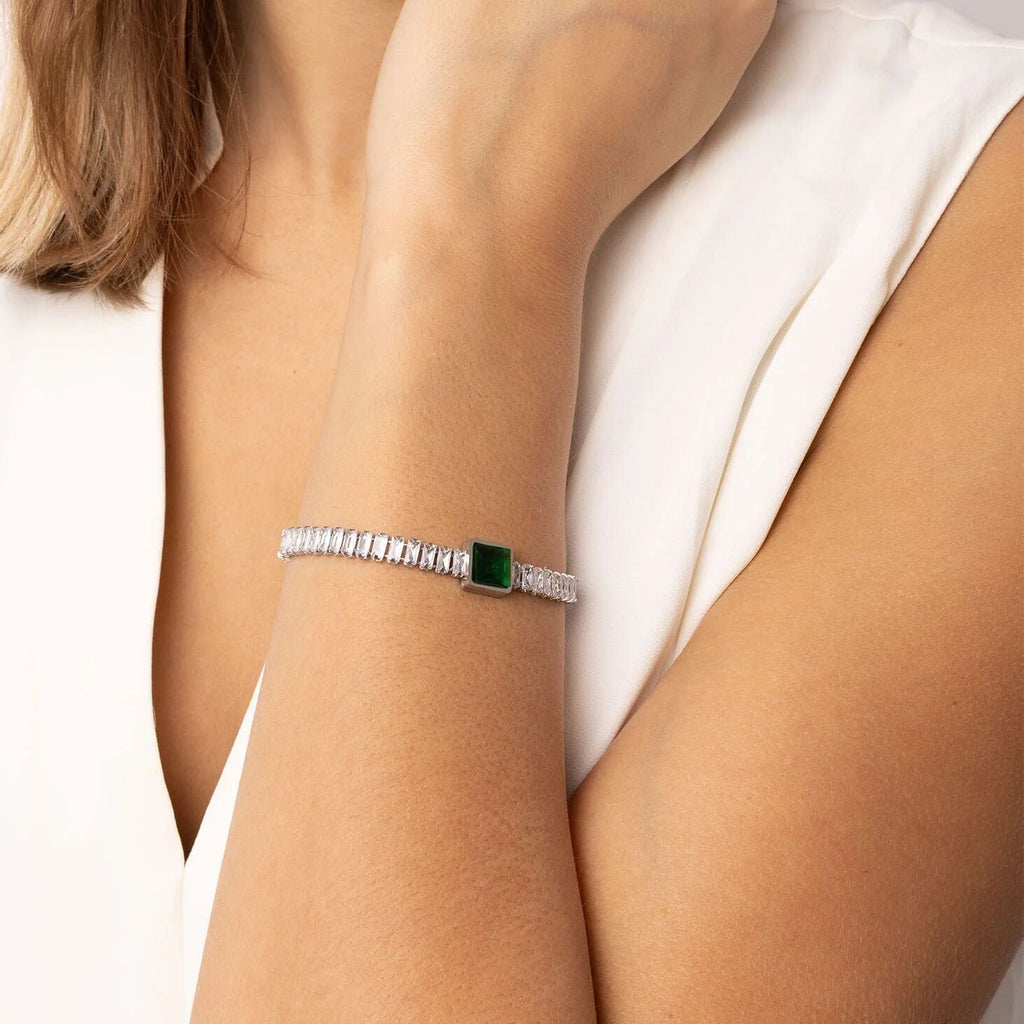 Silver bracelet with a green gemstone on a person's wrist against a white background