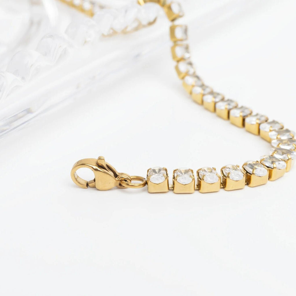 Gold bracelet with clear stones on a white background