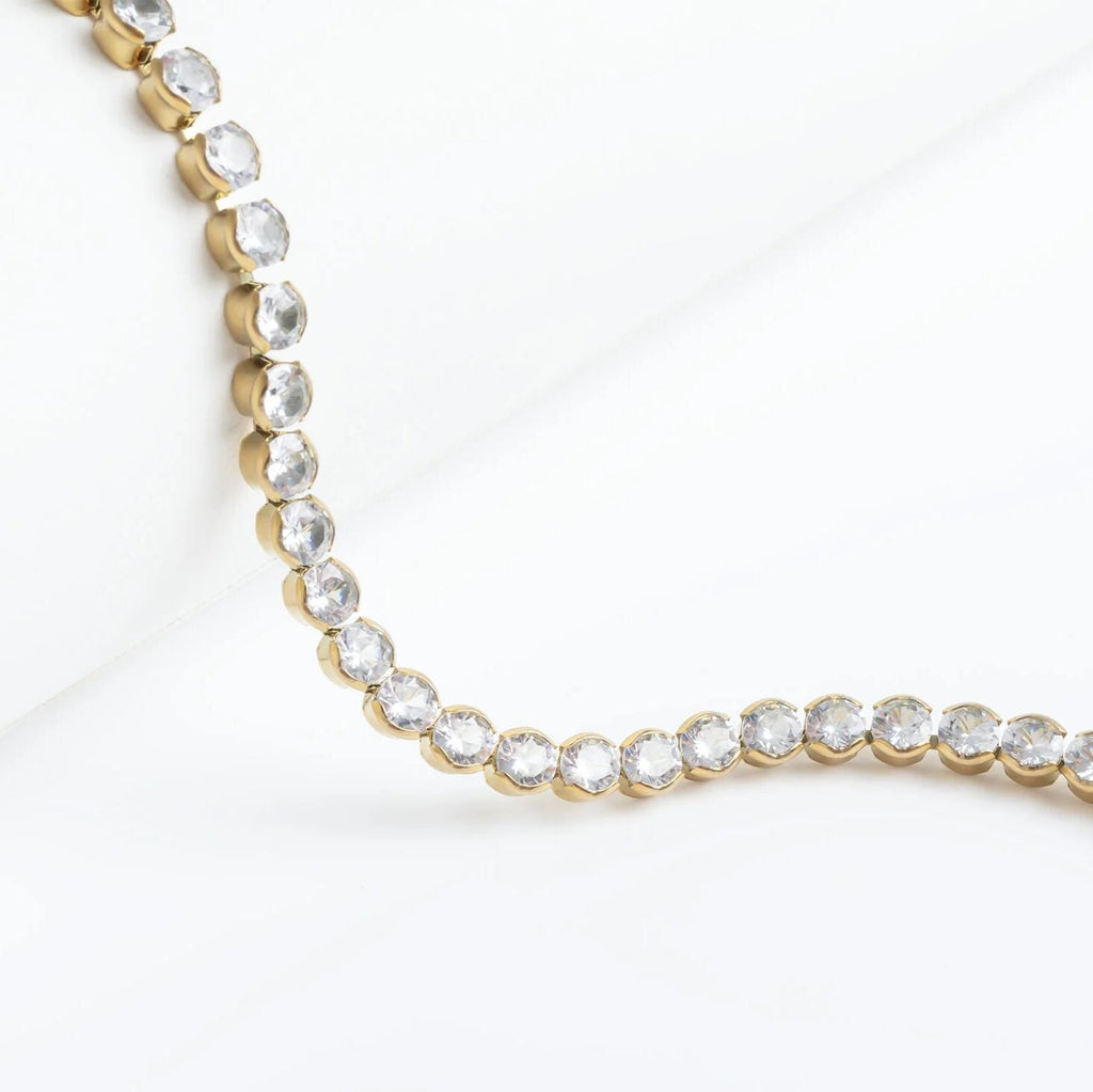 Gold necklace with clear stones on a white background
