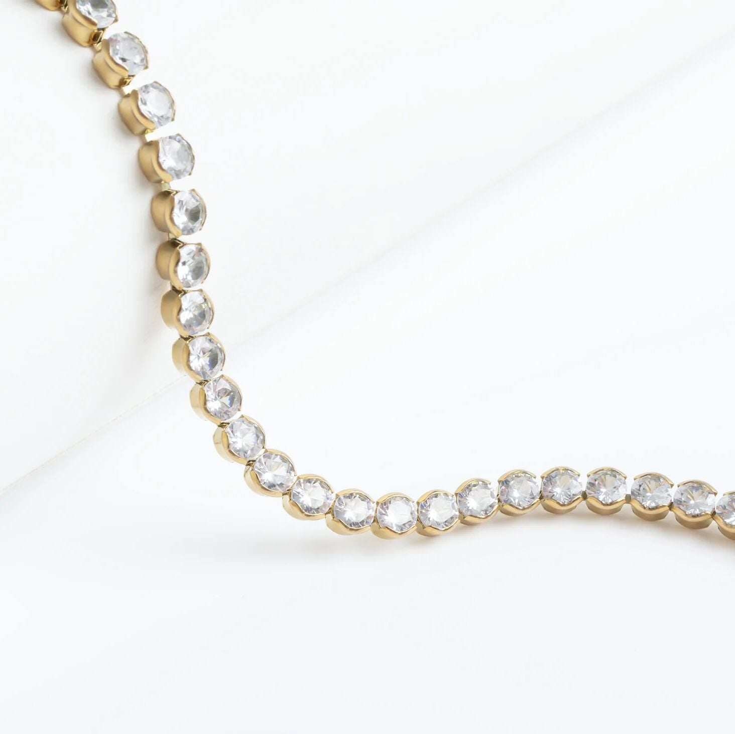 Gold necklace with clear stones on a white background