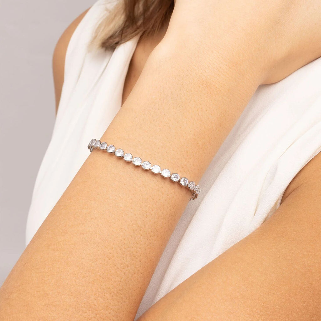 Silver bracelet on a person's wrist with a plain background