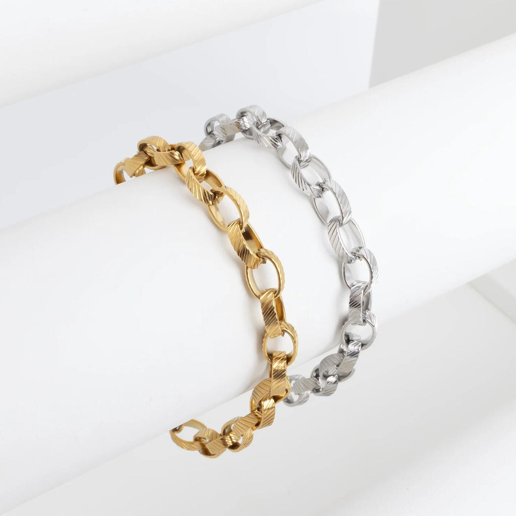 Two chain bracelets, one gold and one silver, on a white background