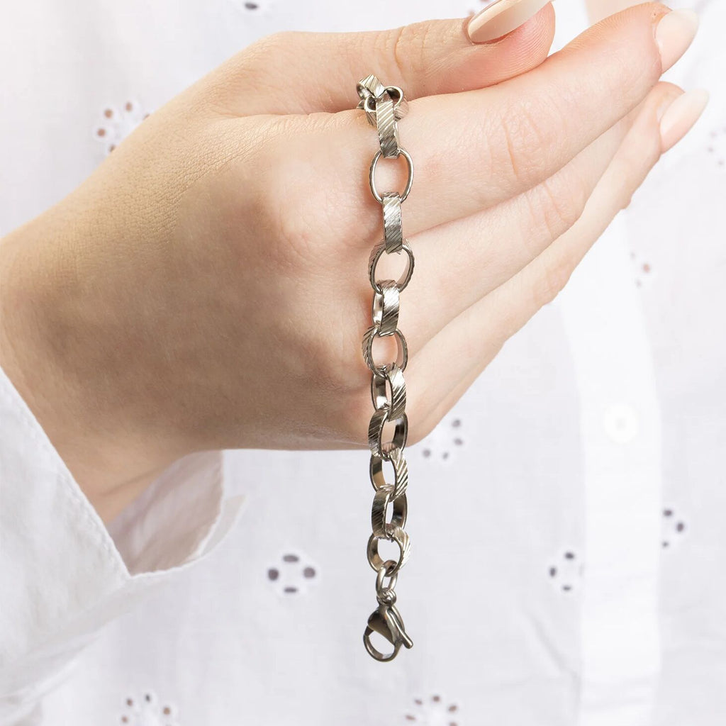 Silver bracelet held in a hand against a white background