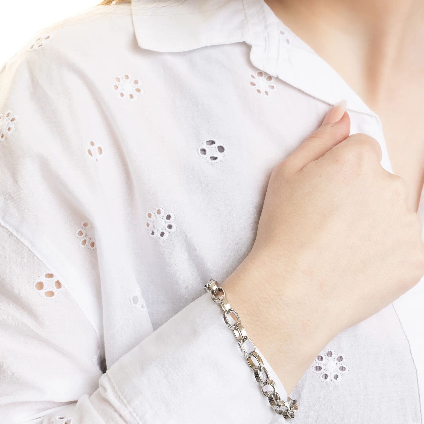 Person wearing a silver bracelet with a white shirt