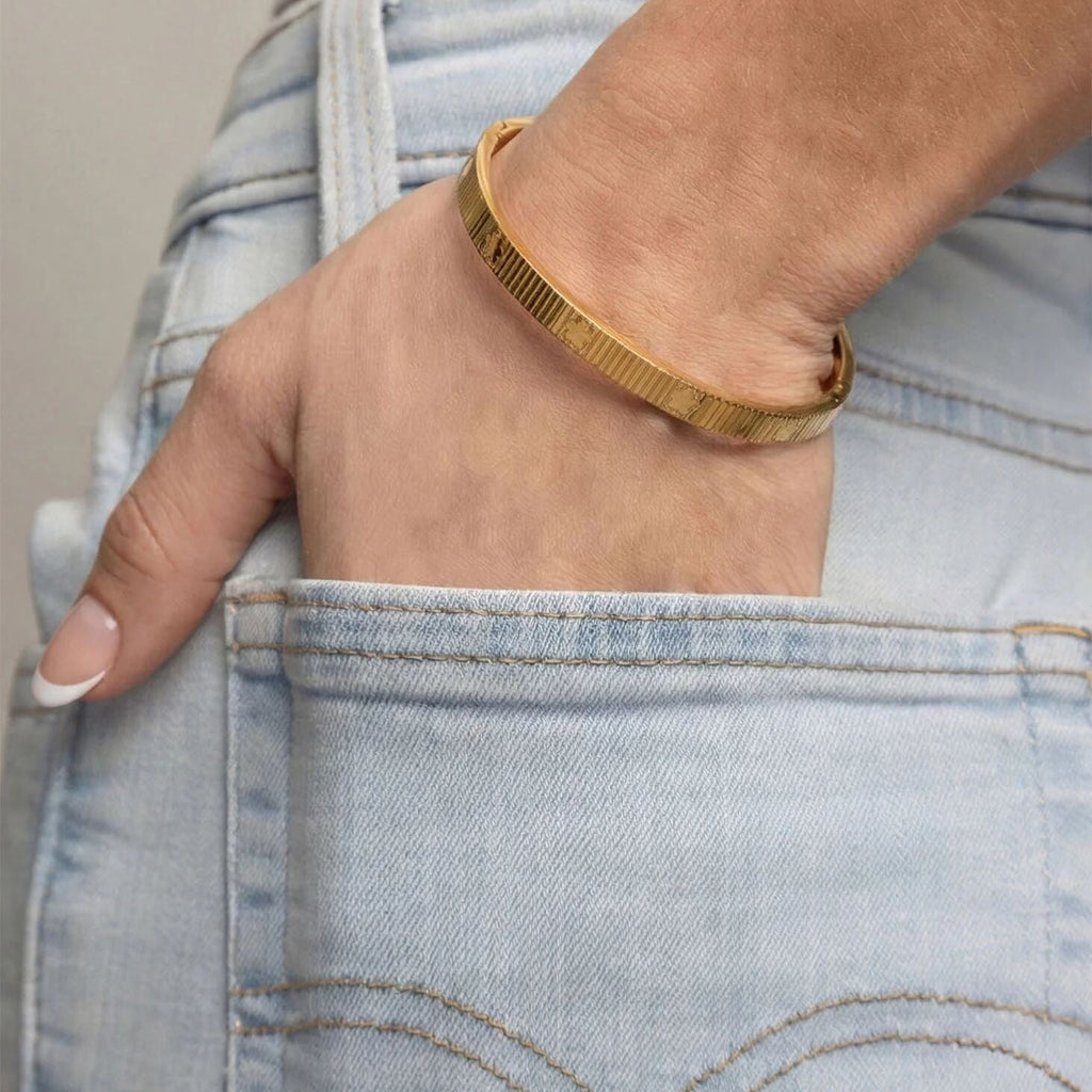 Gold bracelet on a wrist with denim jeans