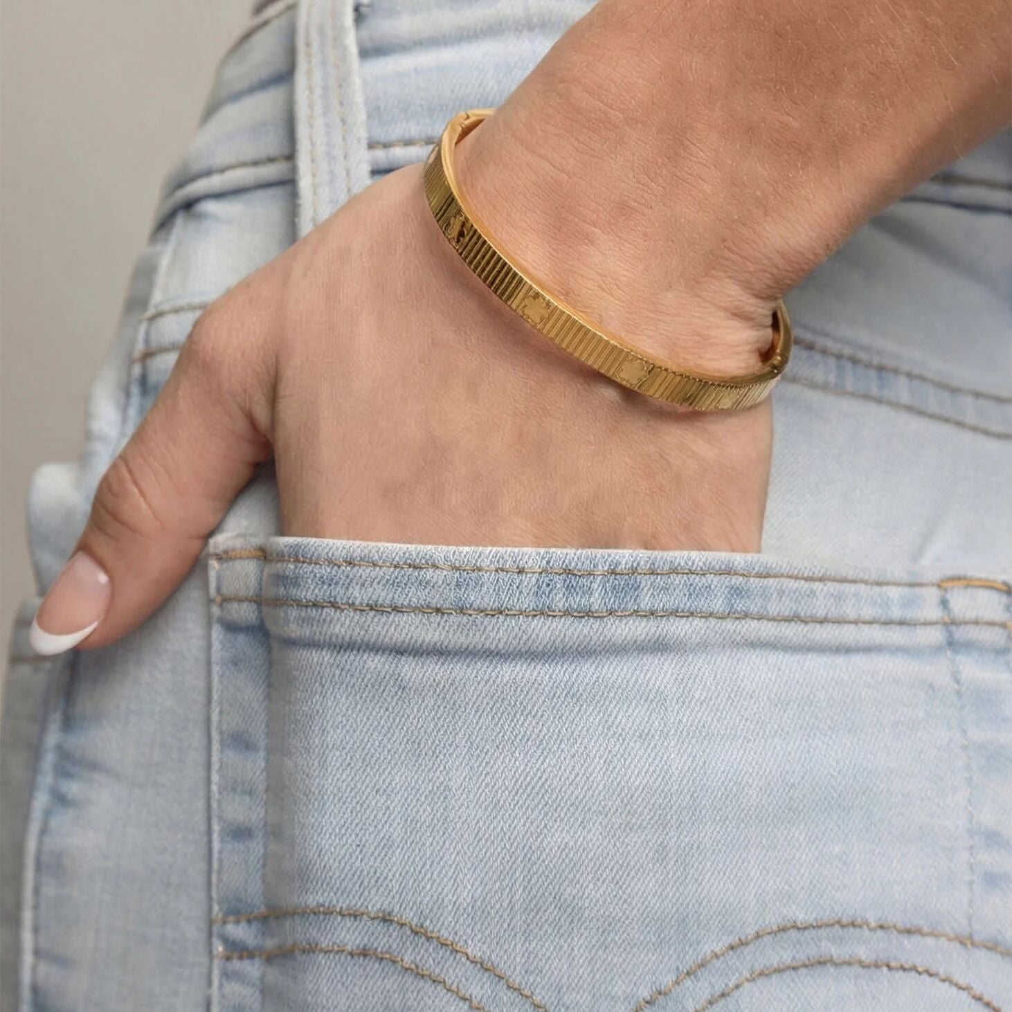 Gold bracelet on a wrist with denim jeans
