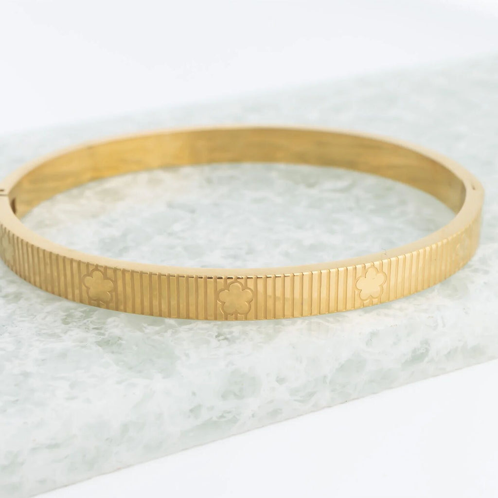 Gold bracelet with engraved design on a marble surface
