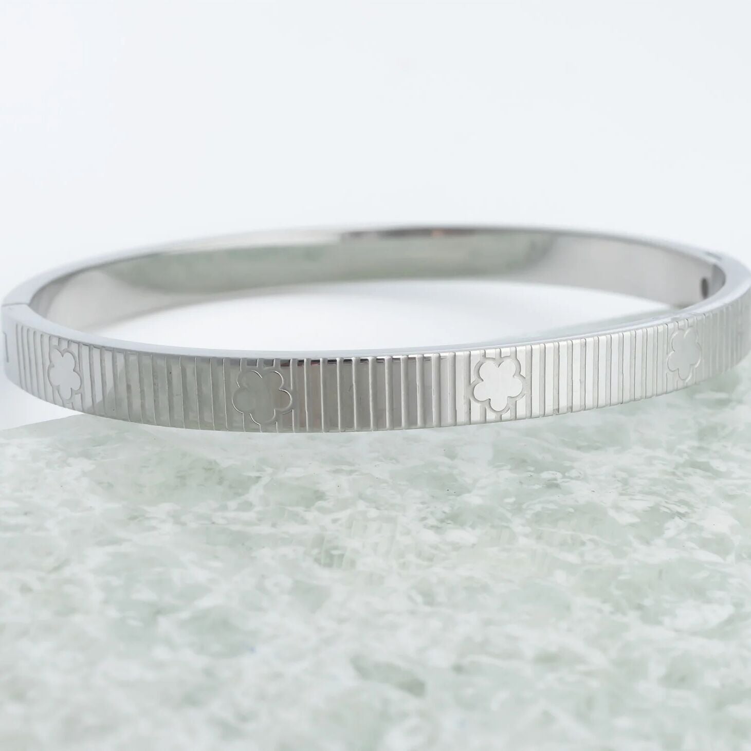 Silver bracelet with engraved patterns on a light marble background