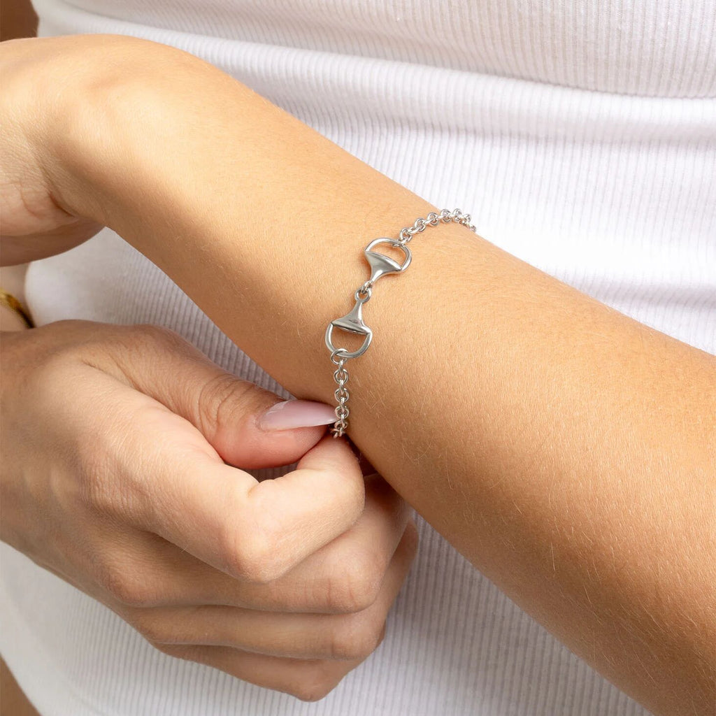 Silver bracelet with a Horsebit design on a wrist against a white background