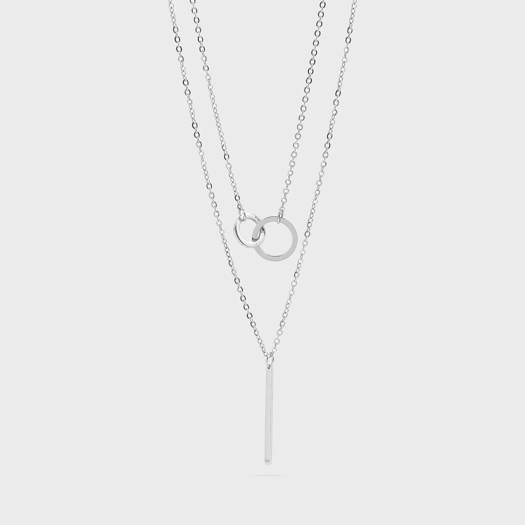 An Interlocked Circle and Bar Layered Charm silver necklaces on a light gray background