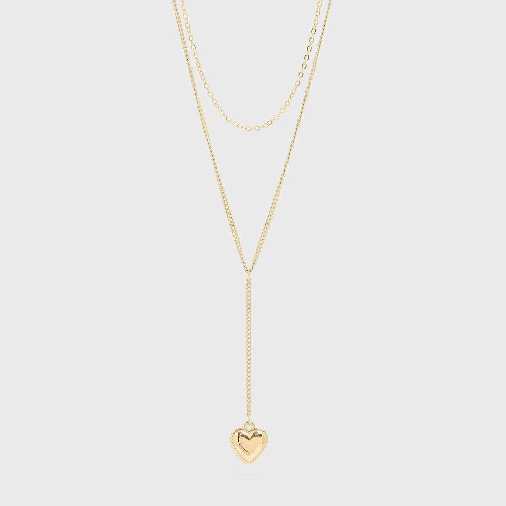 Gold necklace with a heart pendant on a light gray background