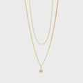 Gold necklace with a small star pendant on a light gray background