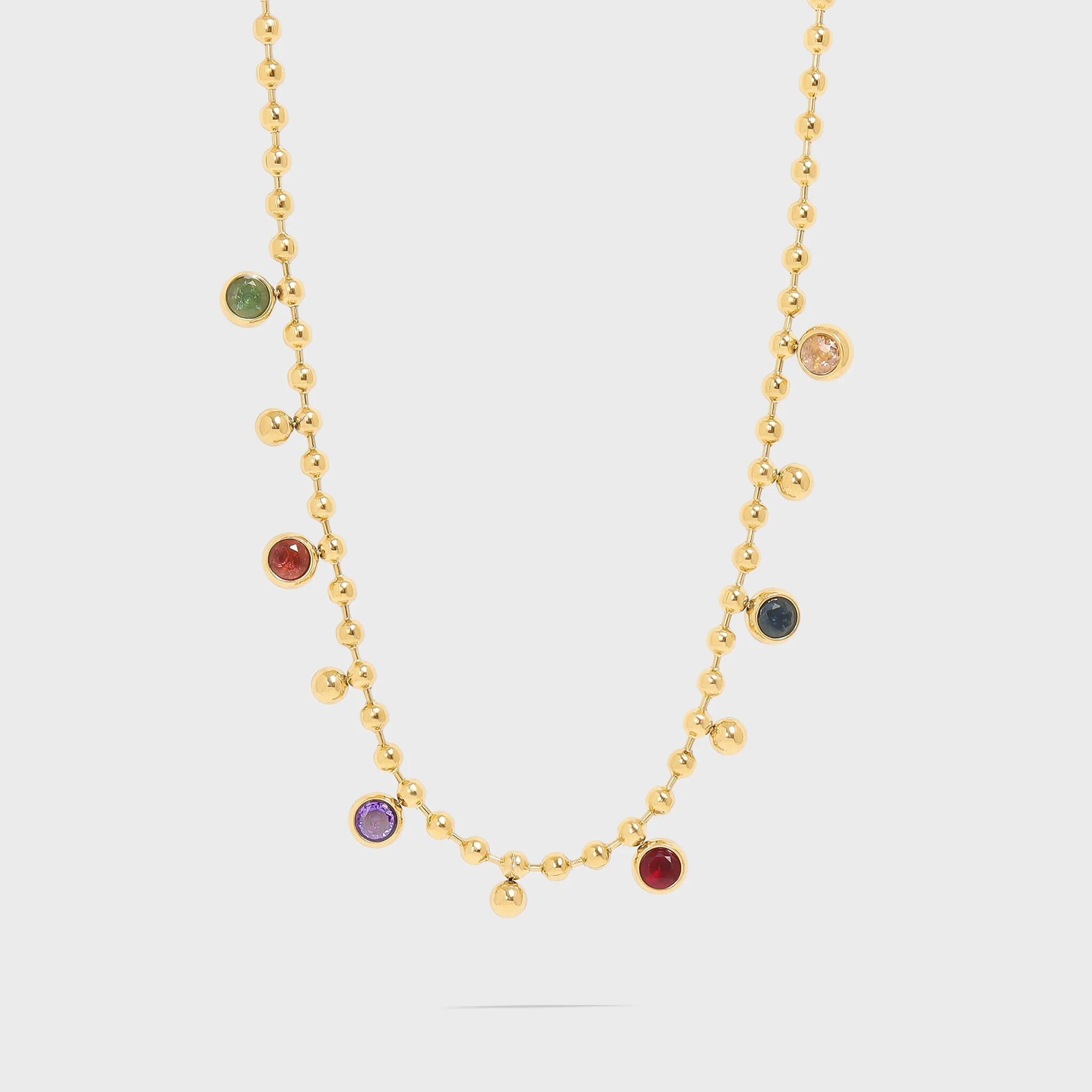 Gold necklace with colorful gemstones on a light gray background