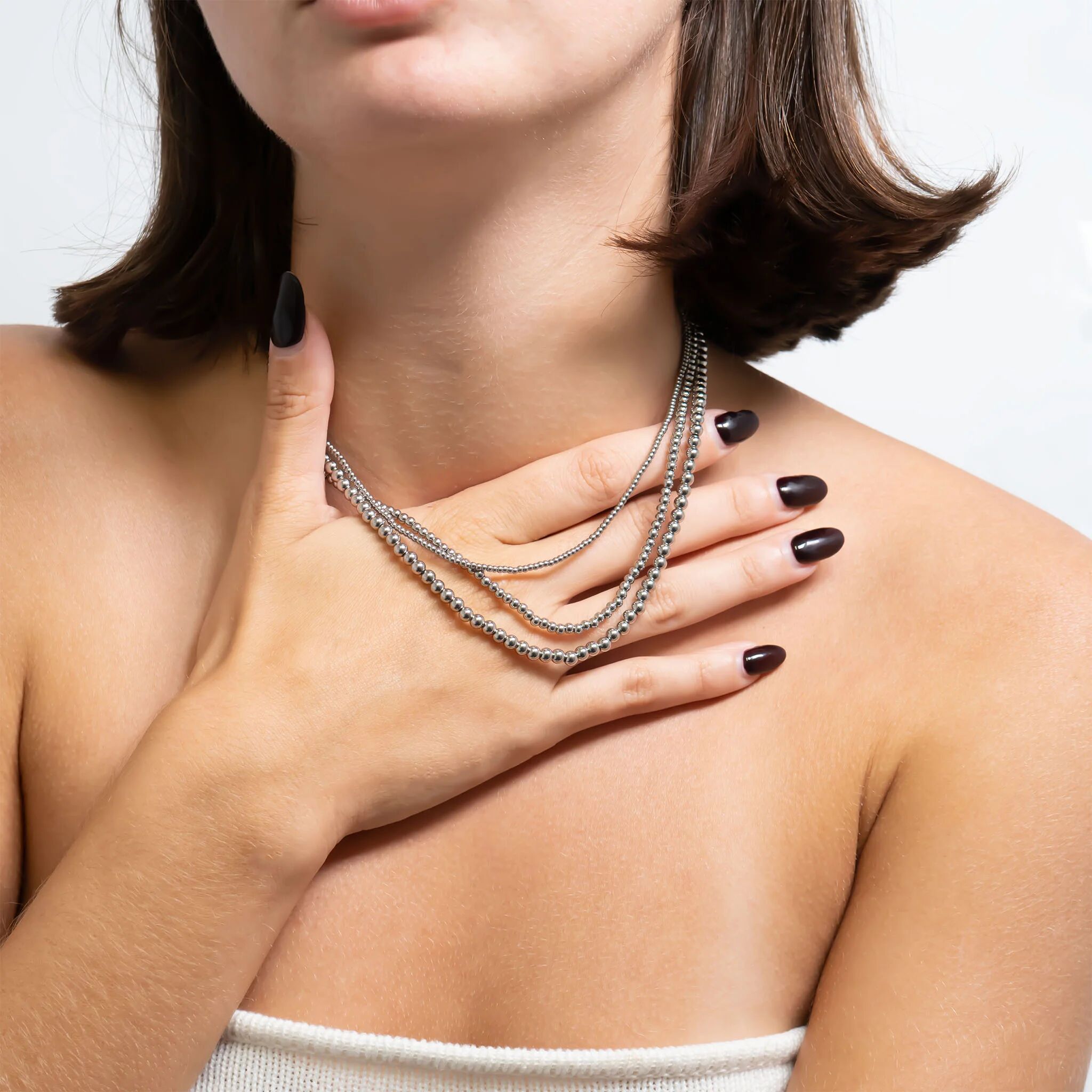 Woman wearing a silver beaded necklace with a neutral background