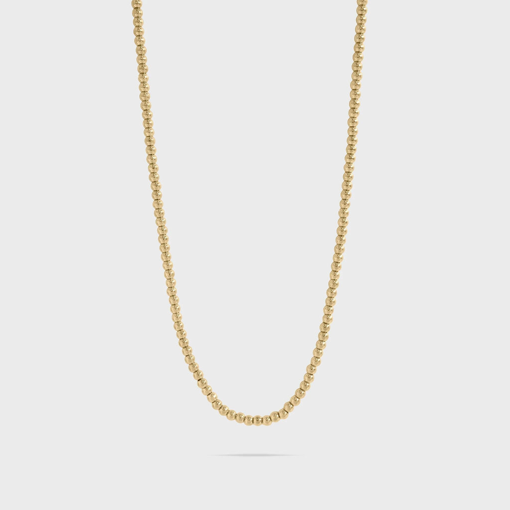 Gold beaded chain necklace on a light gray background