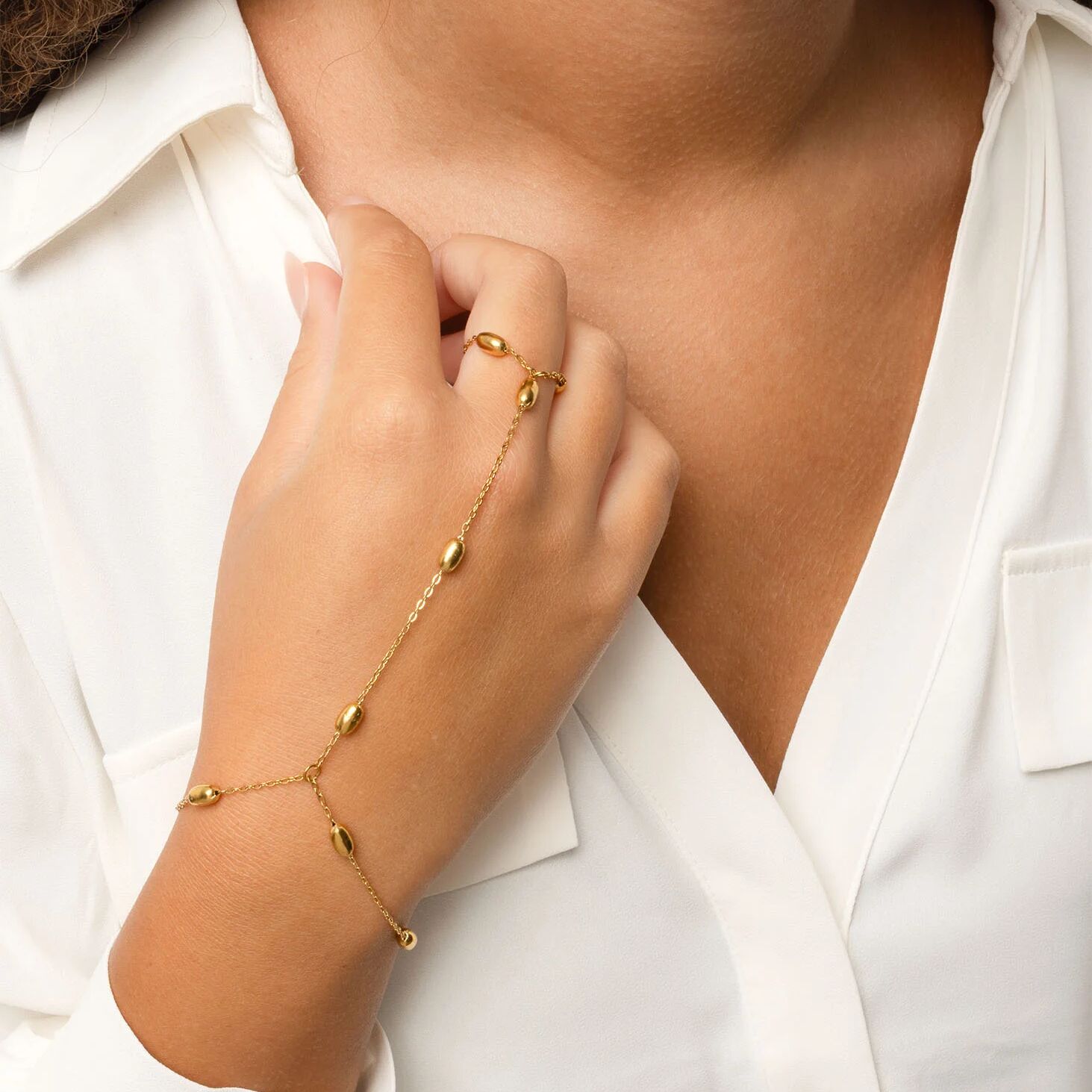 Gold Statement Bead Hand Chain on a person's wrist with a white shirt background