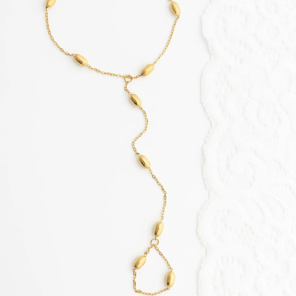 Gold Statement Bead Hand Chain with teardrop-shaped beads on a white background